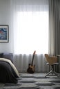 Teenager`s room interior with bed and guitar near window Royalty Free Stock Photo