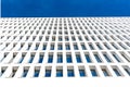 Modern tertiary and businness building with white facade and windows that reflect the blue sky