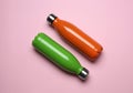 Modern thermo bottles on pink background, flat lay