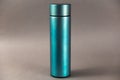 A modern thermos against a gray background. Cylindrical vacuole flask in turquoise color. Container for hot and cold drinks.