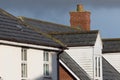 Modern town house roof with slate tiles, chimney and white dormer window Royalty Free Stock Photo