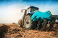 A modern tractor with a trailed plow on the field on a sunny day. Royalty Free Stock Photo
