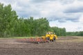 Modern tractor working on field in summer, preparing soil for sowing with seedbed cultivator. Agricultural machinery, farming