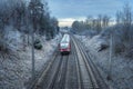 Modern train on rail tracks and snowy nature at dawn