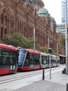 A Modern Tram passing by a Classic and Mid-Century Building