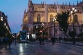 Modern tram at a stop on a street in Seville, Spain, at night, Cathedral on background Royalty Free Stock Photo
