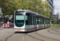 Modern tram traveling through city urban environment along tramlines in the sunshine Royalty Free Stock Photo