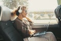 Modern travel lifestyle people with happy smiling woman listening music with headphones and laptop computer sitting and relaxing Royalty Free Stock Photo