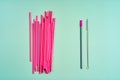 The modern trend towards caring for the environment. A pack of pink plastic beverage straws versus one reusable beverage straw