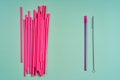 The modern trend towards caring for the environment. A pack of pink plastic beverage straws versus one reusable beverage straw