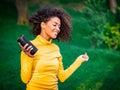 Modern trendy african american girl listening to music by wireless portable speaker.Young beautiful woman enjoying