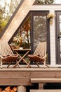 Modern triangle a-frame forest house with terrace, chairs and a table at the entrance Royalty Free Stock Photo