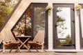 Modern triangle a-frame forest house with terrace, chairs and a table at the entrance Royalty Free Stock Photo