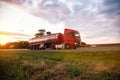 A modern truck with a semi-trailer tanker transports dangerous goods against the backdrop of a sunset in summer. Liquid cargo