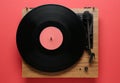 Modern turntable with vinyl record on red background, top view