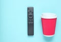 Modern TV remote and paper cup of coffee on blue pastel background. Top view, minimalism. Royalty Free Stock Photo