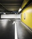 Modern underground parking garage with an arrow on the floor indicating the direction and a yellow wall with the floor number Royalty Free Stock Photo