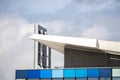 Modern urban architecture blue and aqua building angled roofline with chrome stainless steel chimneys reaching to the cloudy sky