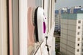 A modern vacuum robot window washer washes glass in an apartment on a balcony. View outside from the street. Safety from