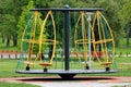 Modern variation of outdoor public playground equipment Merry-go-round with climbing nets and rotating cages surrounded with grass