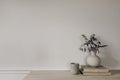 Modern vase with dry eucalyptus tree branches on wooden table. Candle in concrete candleholder, pile of old books. White Royalty Free Stock Photo