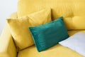 Sofa with mustard velvet textile and pillows, closeup