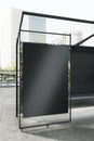 Modern vertical glass bus stop with empty black billboard and reflections on city background. Mock up Royalty Free Stock Photo