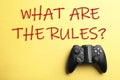 Modern video game controller with text WHAT ARE THE RULES on background, top view