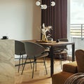 Modern and vintage dining room with brown wooden table, grey chairs and stylish chandelier. Minimalistic white wall and brown Royalty Free Stock Photo