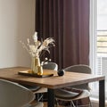 Modern and vintage dining room interior with brown wooden table, grey chairs and stylish chandelier. White wall and brown curtains Royalty Free Stock Photo