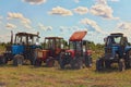 Modern and vintage tractors lined up in farm field. Figure piloting competition at the field ended. Sunny summer day Royalty Free Stock Photo