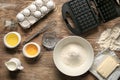 Modern waffle maker with ingredients on wooden table Royalty Free Stock Photo