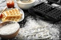 Modern waffle maker with ingredients on wooden table Royalty Free Stock Photo