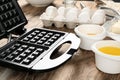 Modern waffle maker with ingredients on wooden table Royalty Free Stock Photo
