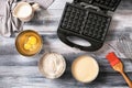 Modern waffle maker with ingredients on wooden table Royalty Free Stock Photo