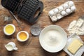 Modern waffle maker with ingredients on wooden table Royalty Free Stock Photo