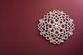 A modern wall hanging with intricate hexagonal designs, isolated on a solid maroon background