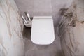 Modern wall-mounted toilet in the bathroom with gray porcelain stoneware tiles. Hygienic shower and toilet brushes. Royalty Free Stock Photo