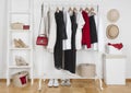 Modern wardrobe interior with different female clothes, hats and shoes