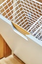 Modern wardrobe with opened metal mesh laundry basket. Wooden wardrobe with light gray cabinet doors. Close-up