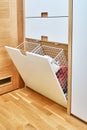 Modern wardrobe with opened metal mesh laundry basket. Wooden wardrobe with light gray cabinet doors