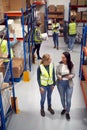 Modern Warehouse With Fulfilment Staff Picking Items From Shelves And Manager Using Digital Tablet