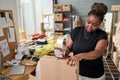 Modern warehouse worker sealing cardboard box with cellotape by workplace Royalty Free Stock Photo