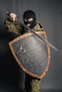 Modern warrior with medieval weapons in his hands. A soldier defends himself with a shield and attacks with a sword.