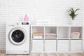 Modern washing machine near brick wall in laundry room