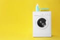 Modern washing machine with stack of towels and detergent on yellow background. Laundry day Royalty Free Stock Photo