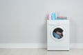 Modern washing machine with stack of towels and detergents near white wall, space for text. Laundry day Royalty Free Stock Photo