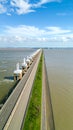 Modern water barrier with road and wind turbines offshore under a blue sky with clouds Royalty Free Stock Photo