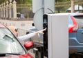 Young driver woman pressing a button on parking machine.