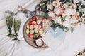 Modern wedding bouquet, wedding rings, stylish invitation, perfume bottle, delicious macarons and green glasses for champagne on